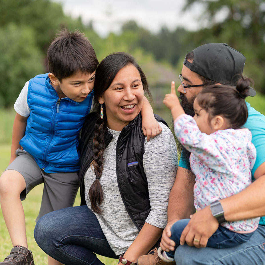 Native American family playing together on a soccer field Parents with two young children outdoors.